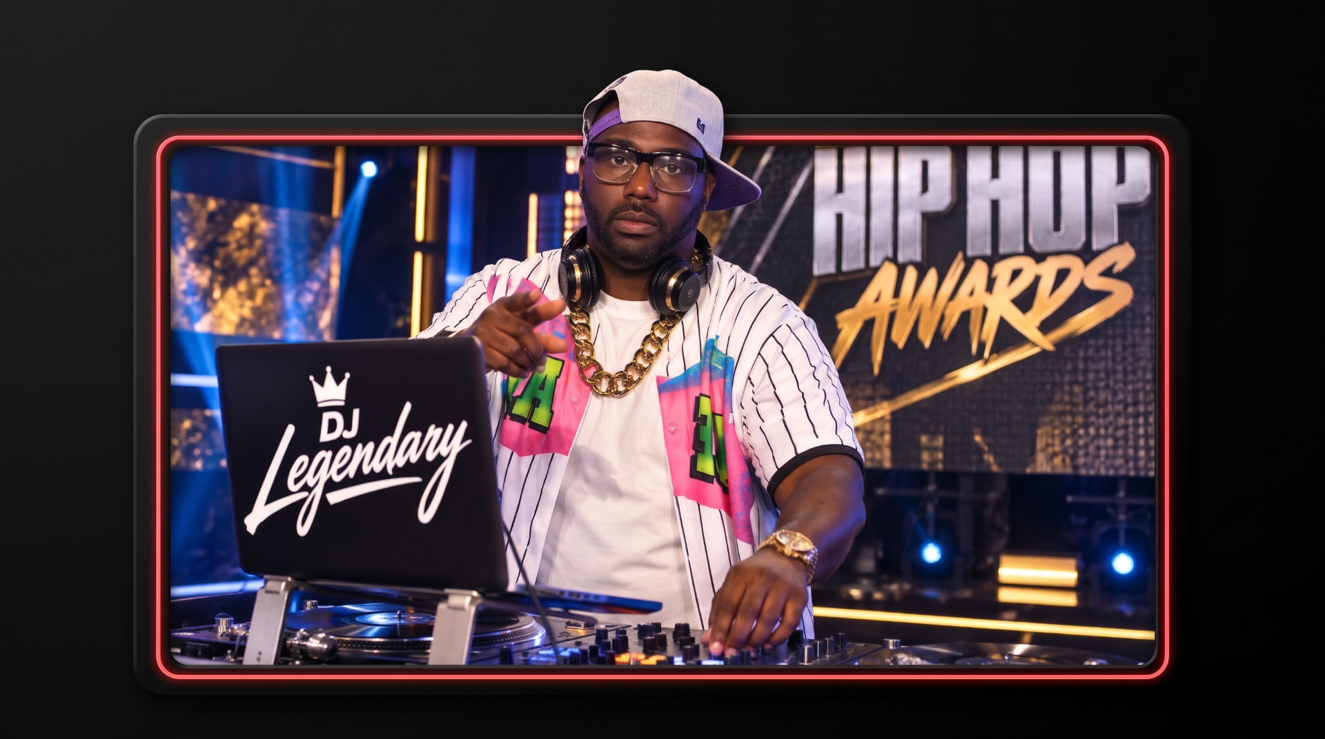 DJ Legendary at his rig in a pinstripe jersey and cap, framed in neon on a Hip Hop Awards stage